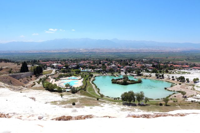 People relaxing in the turquoise blue thermal waters of the white travertine terraces in Pamukkale.
