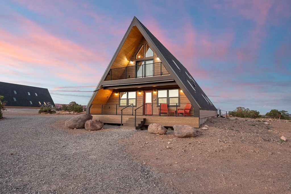 A modern A-frame cabin called Pinyon House with large glass windows and wooden exterior.