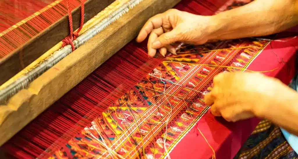 An artisan performing traditional Sadu weaving with colorful threads.