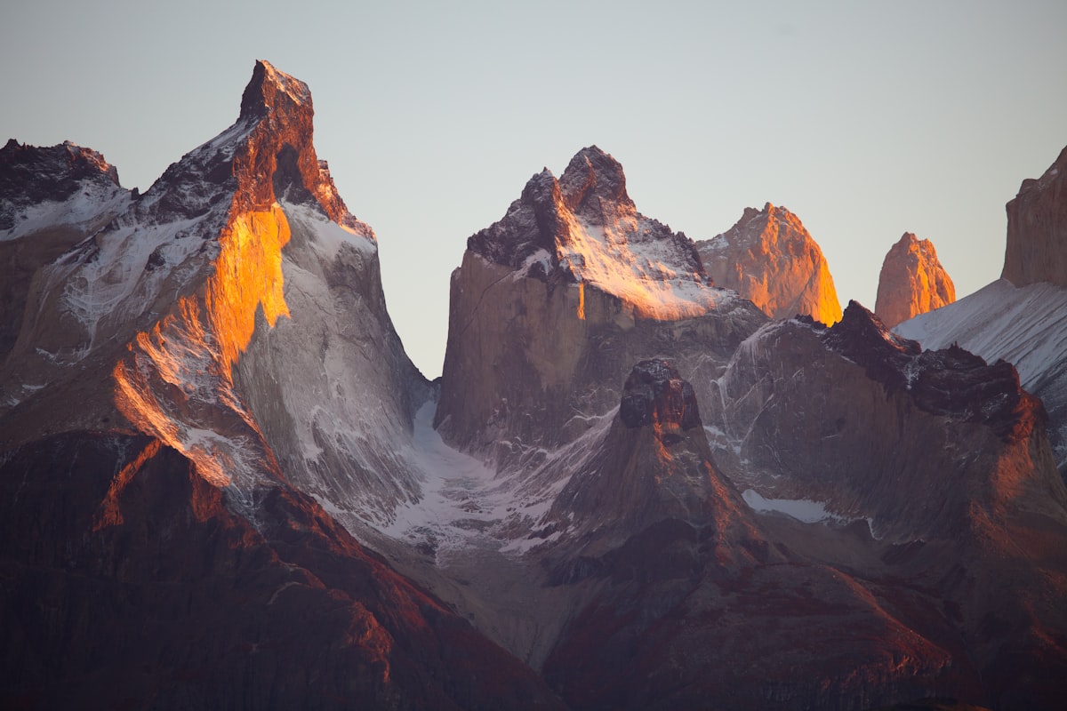 Snow-covered mountain peaks and evergreen trees under a bright winter sun.