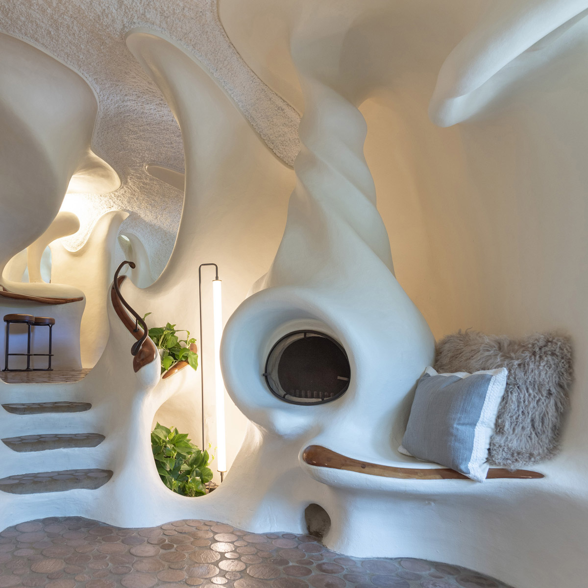 The bedroom area of the Bloomhouse with intimate rounded walls and a view of the surrounding nature through a curved window.