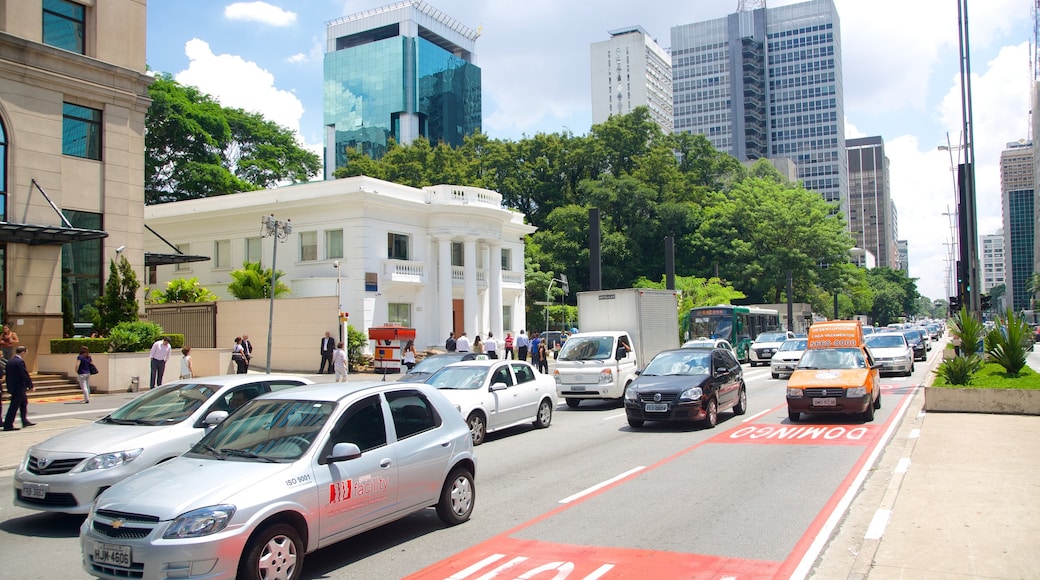 Pedestrians walking along the wide sidewalks of Paulista Avenue with modern buildings in the background.