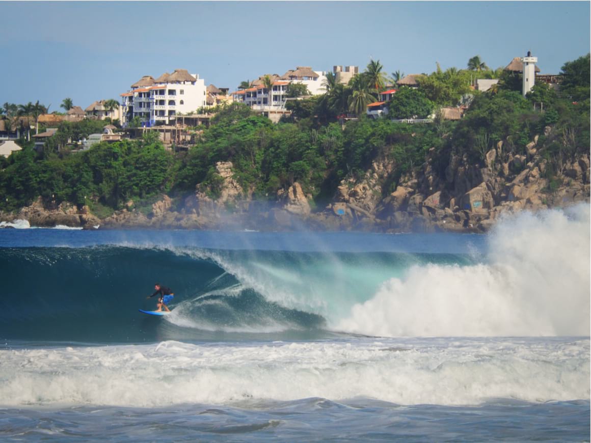 A professional surfer riding inside a large breaking wave at Playa Zicatela.