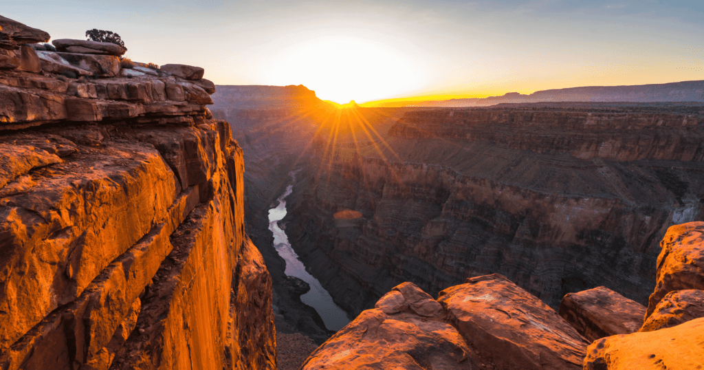A panoramic sunset view over the layered red rocks of the Grand Canyon South Rim.