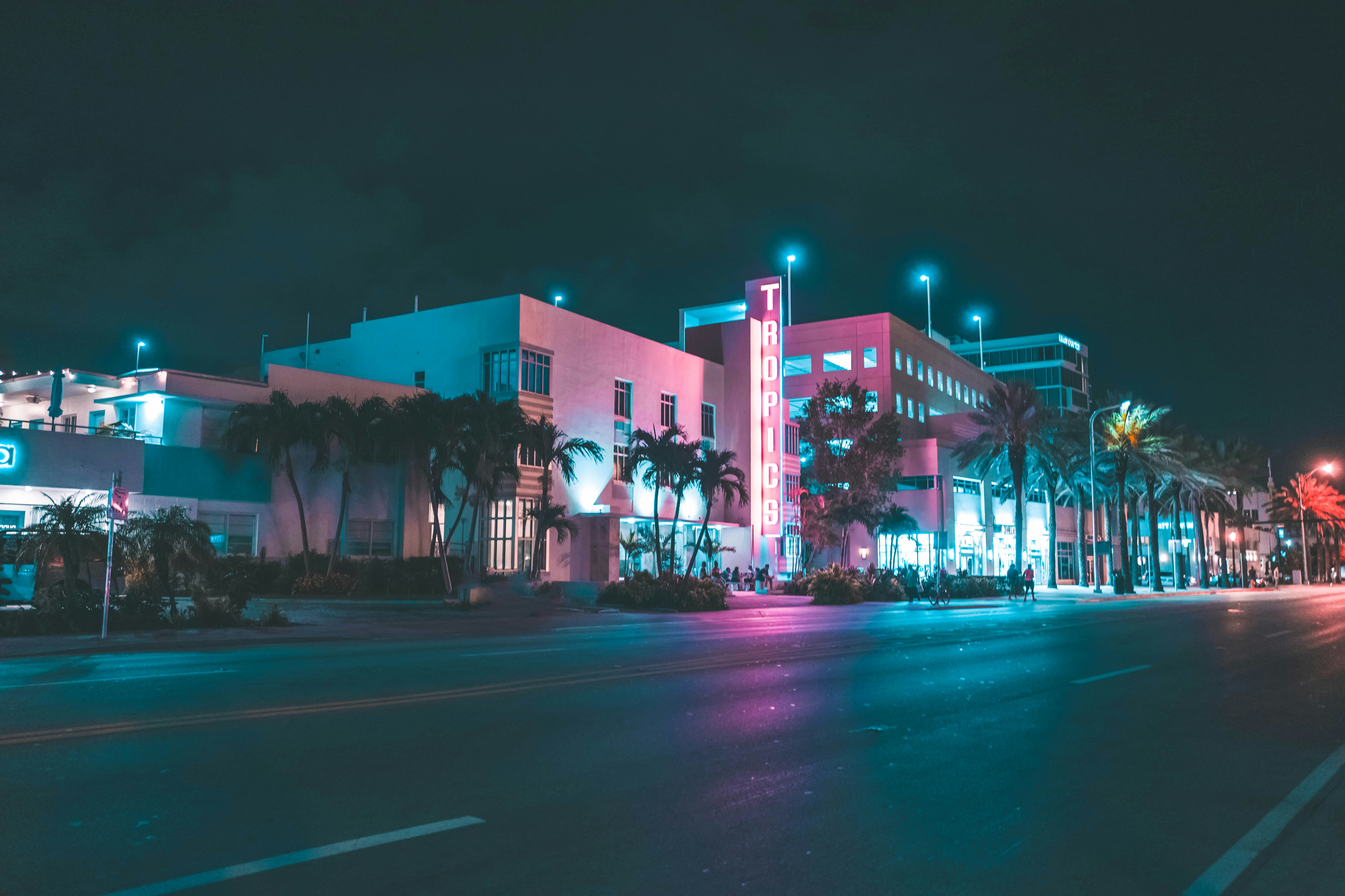 The glowing neon signs of historic Art Deco hotels on Ocean Drive during twilight.