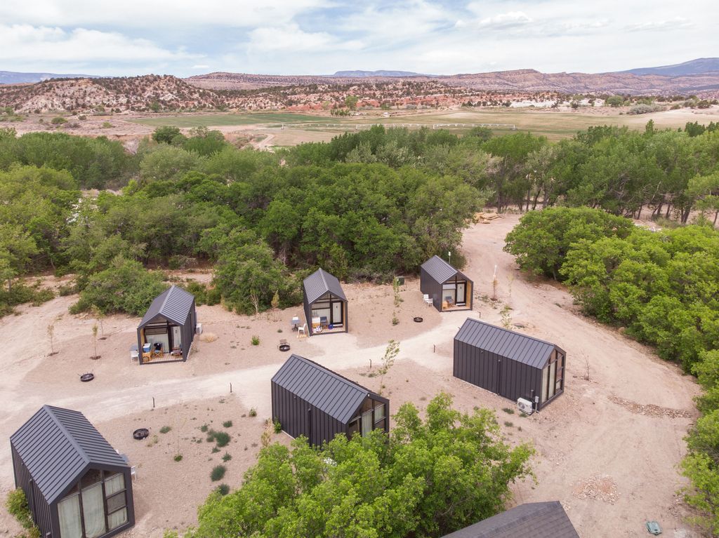 A minimalist tiny cabin at Ofland Escalante under a bright blue sky.
