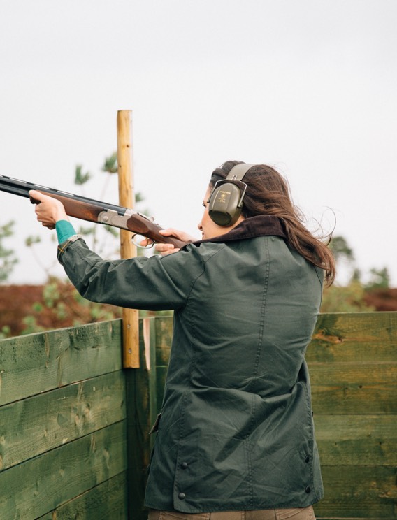 A woman wearing a practical jacket while clay pigeon shooting on a misty day.