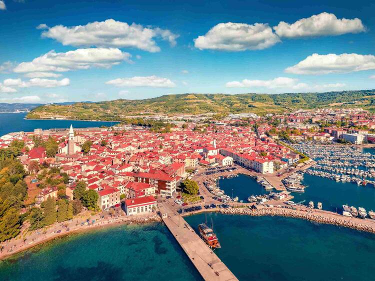 A peaceful narrow street in Izola, Slovenia, showcasing historical stone buildings and Venetian architectural influences.