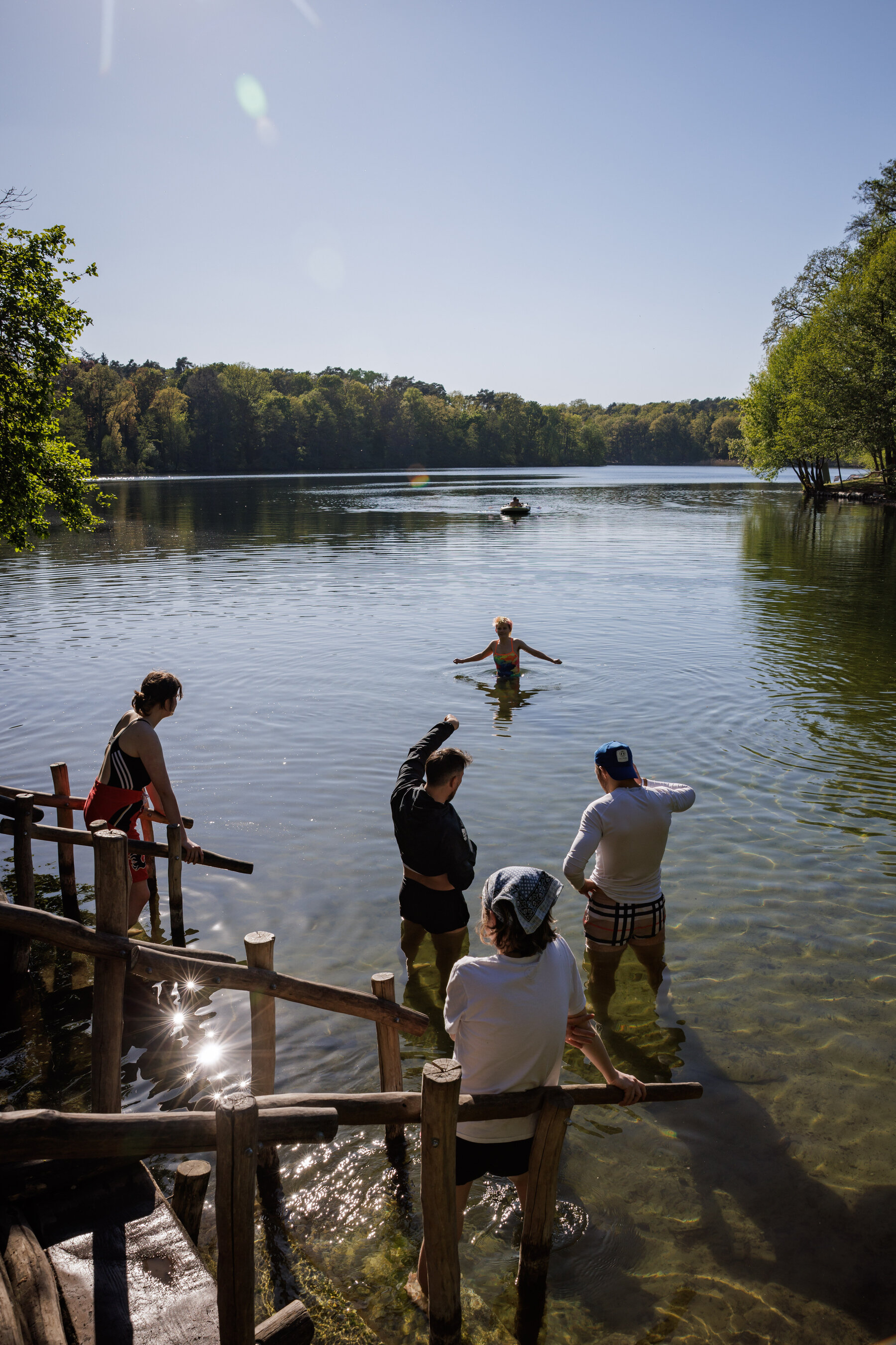 People swimming and lounging on the forest-lined shores of Schlachtensee.
