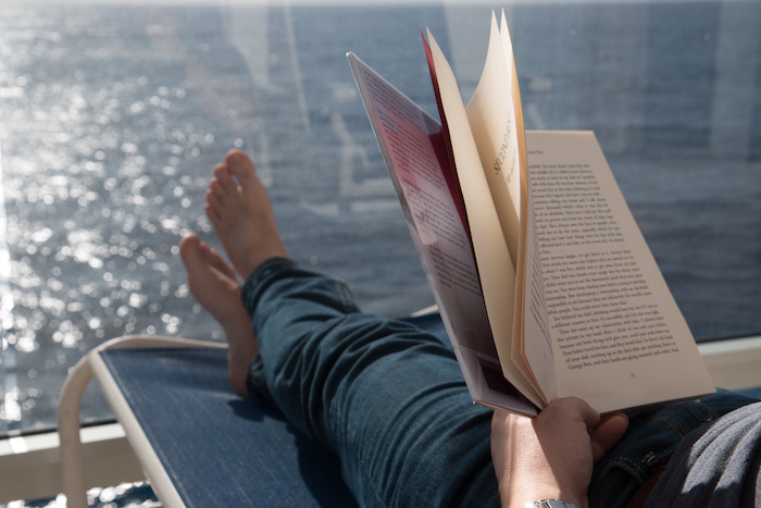 An aerial perspective of a white luxury cruise ship navigating through deep blue ocean waters.