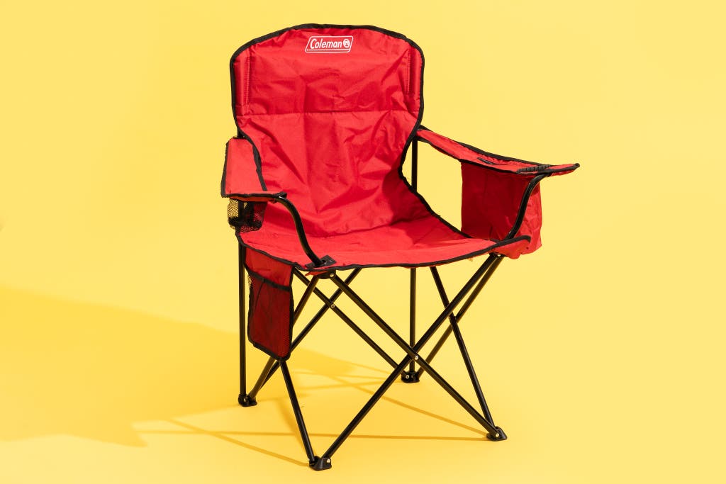 A classic red Coleman folding camping chair with armrests and a cup holder.
