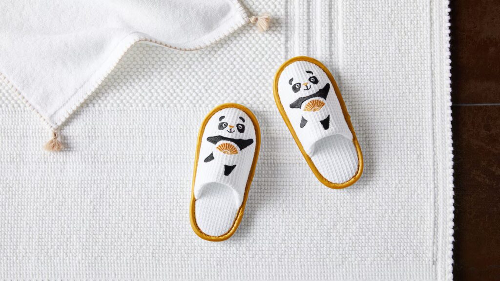 Tiny white hotel slippers designed for children with a logo.