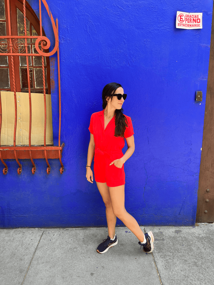 A person in a red outfit standing against a bright, textured blue wall in the Roma Norte neighborhood.