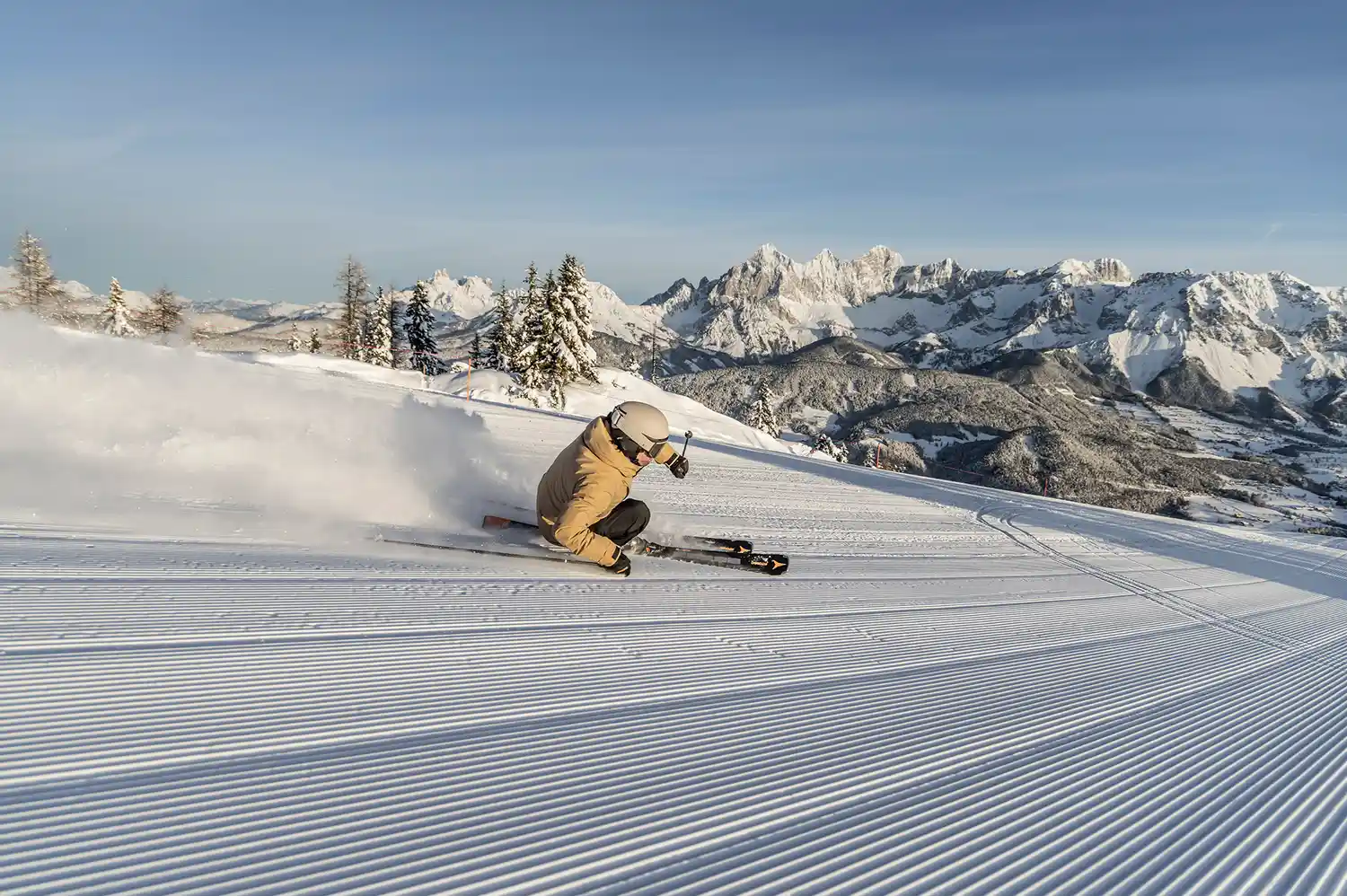 A skier in red gear performing a high-speed turn on a perfectly groomed white snow slope at Reiteralm.
