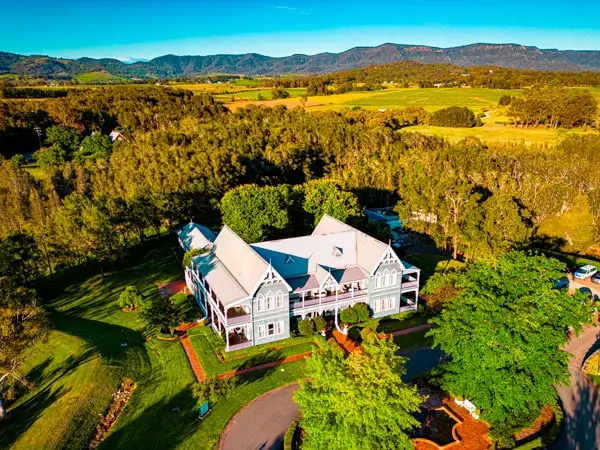 A historic grand building surrounded by manicured lawns and vineyards.