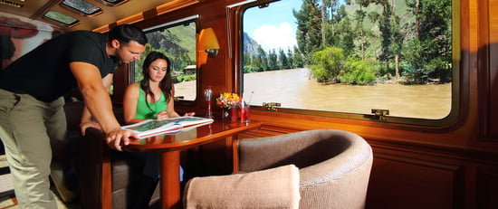 A private, high-end train carriage with plush seating and ornate wooden details.