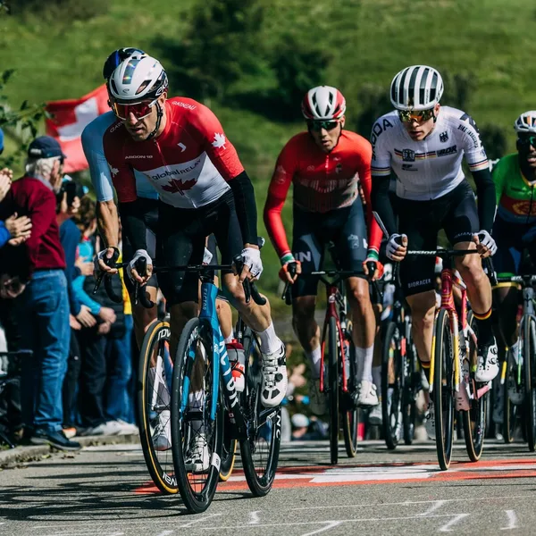 Professional cyclists competing in a road race with spectators in the background.