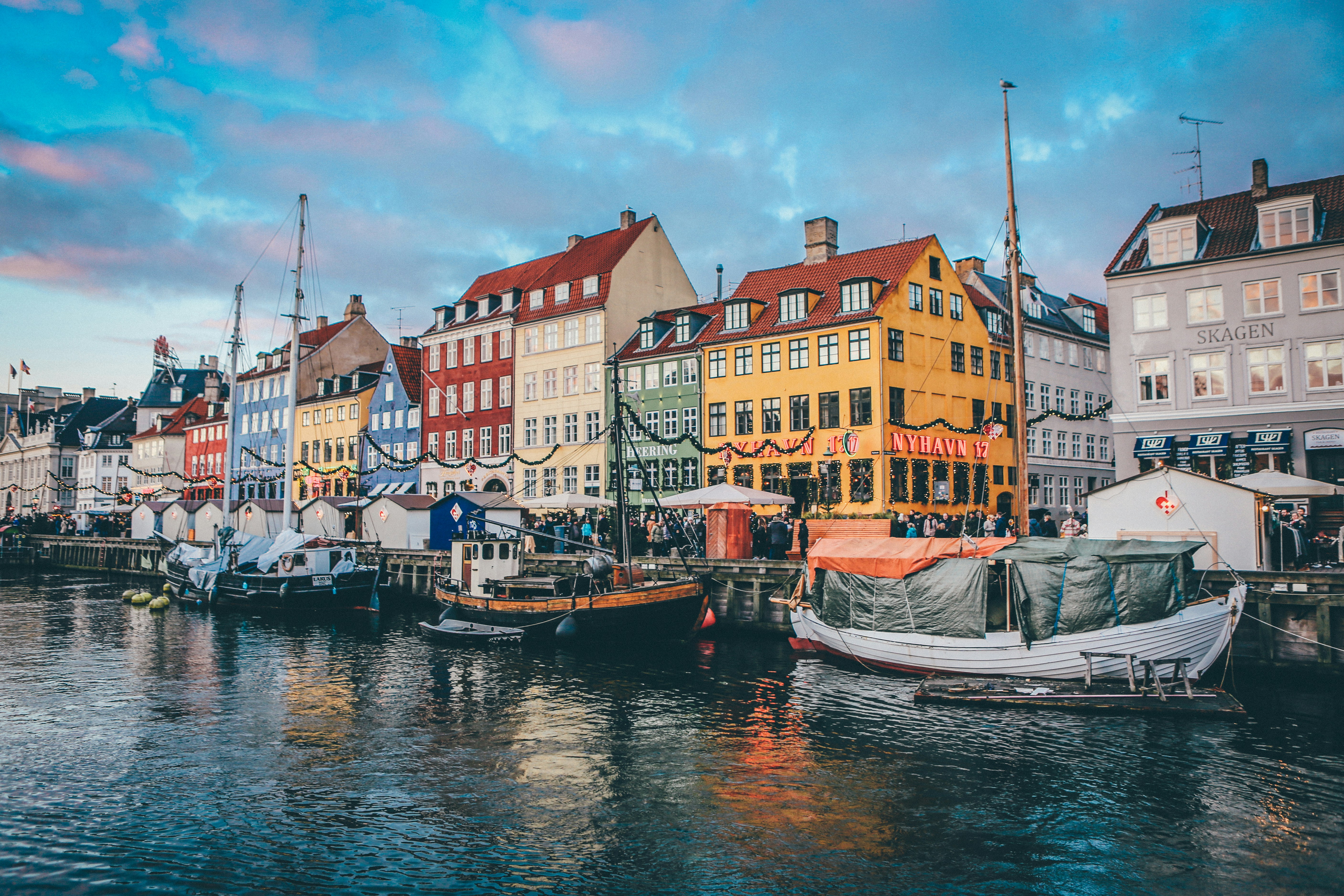 Brightly colored historic buildings and wooden boats along the Nyhavn canal in Copenhagen.