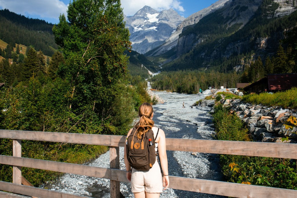 A scenic view of a traditional Swiss mountain village with a red train passing through a lush green valley.