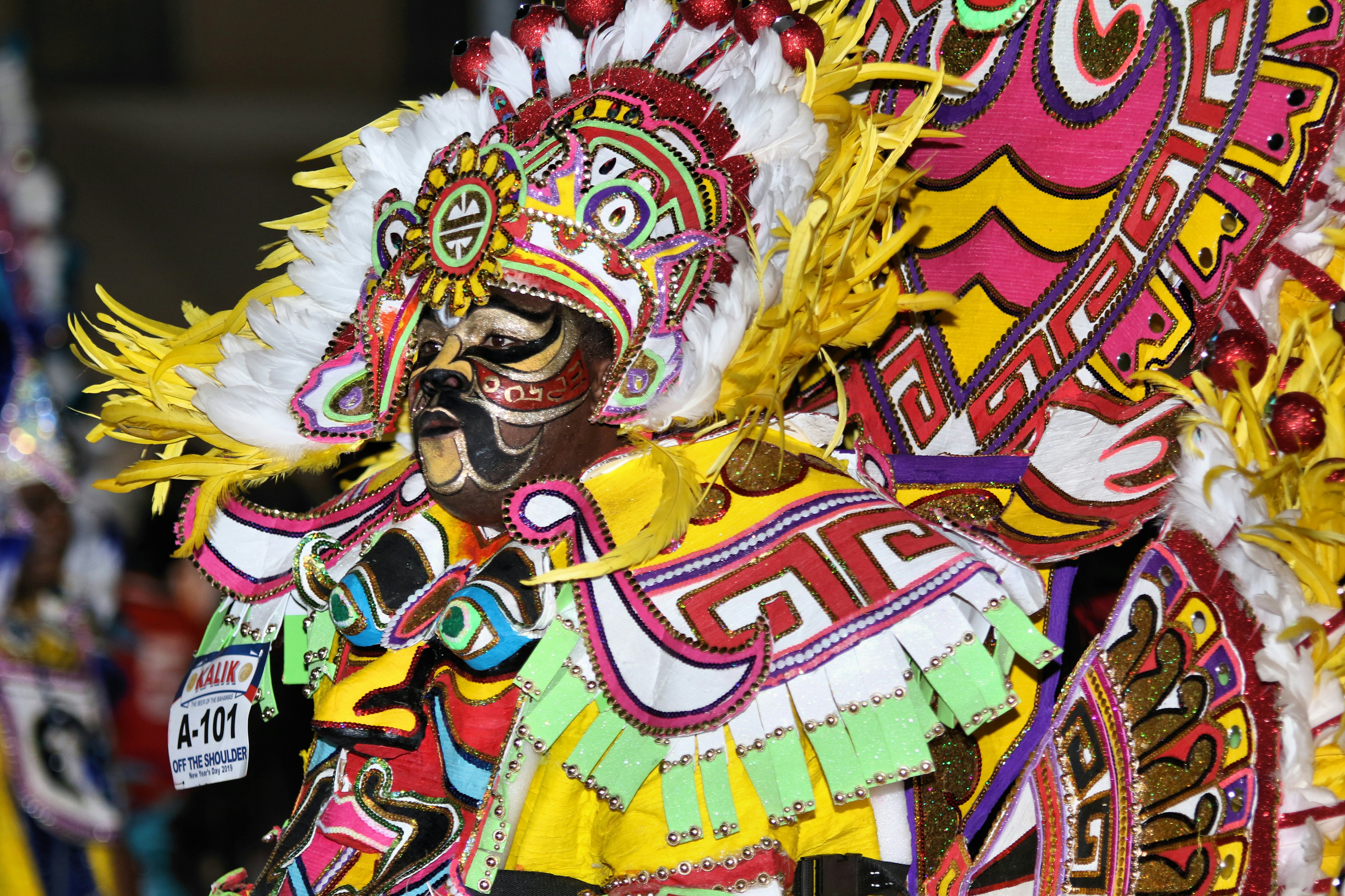 A participant in a Junkanoo parade wearing an elaborate, colorful feathered and beaded costume.