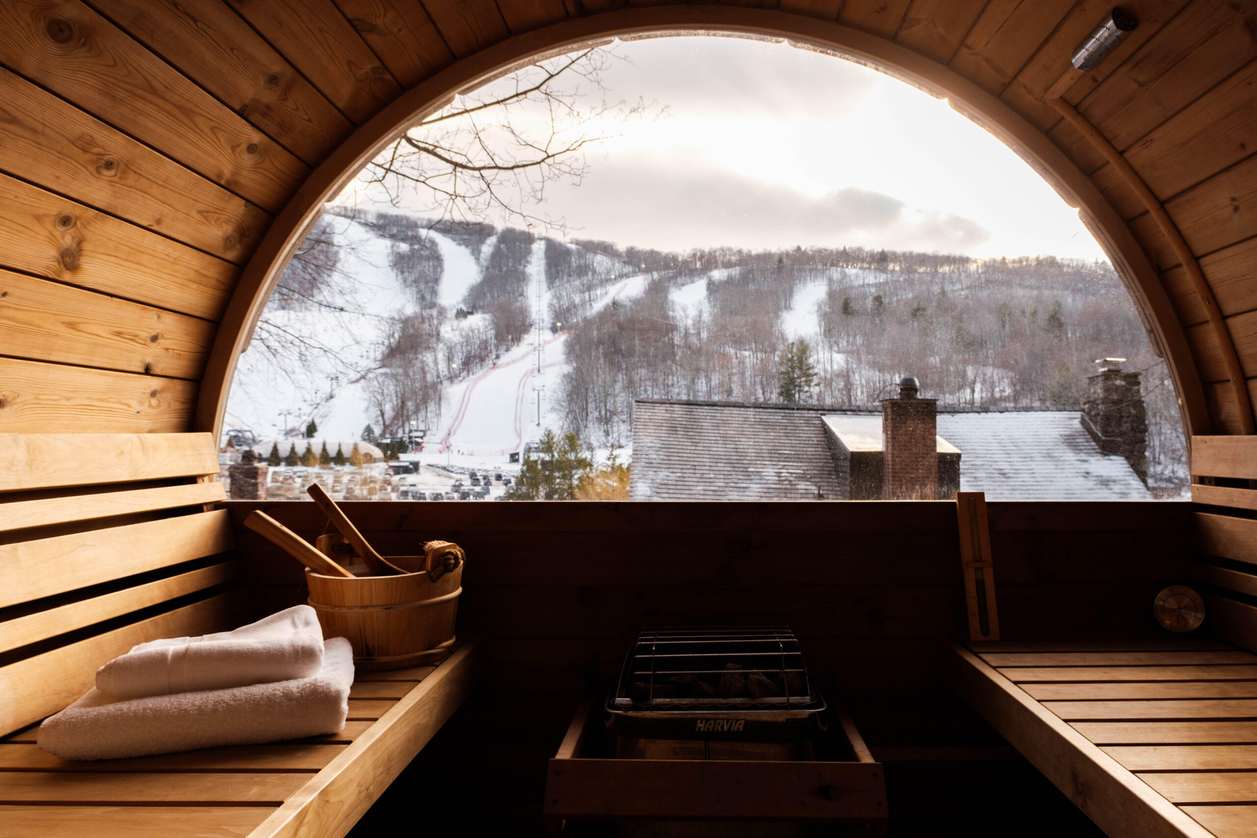 An outdoor wooden sauna at Little Cat Lodge with a view of the Catamount ski slopes in the background.