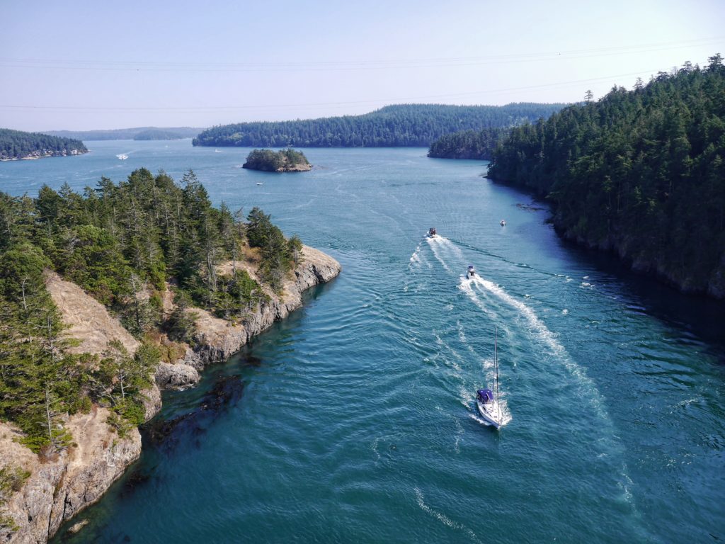 Aerial perspective of the Deception Pass Bridge spanning the turbulent turquoise waters between two islands.